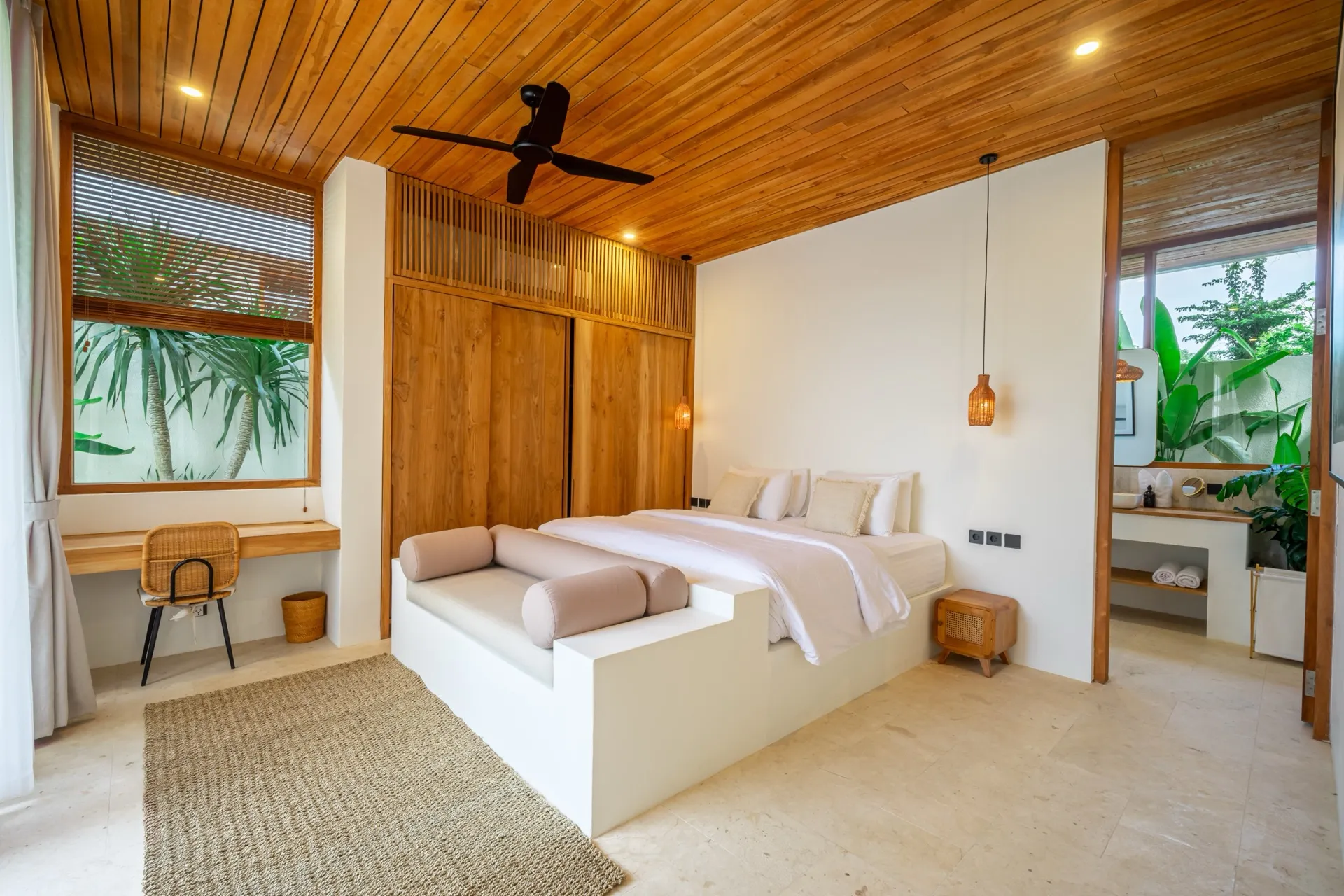 A bedroom at Villa Lila with a built-in daybed at the foot of the bed, teak wardrobes and a garden window