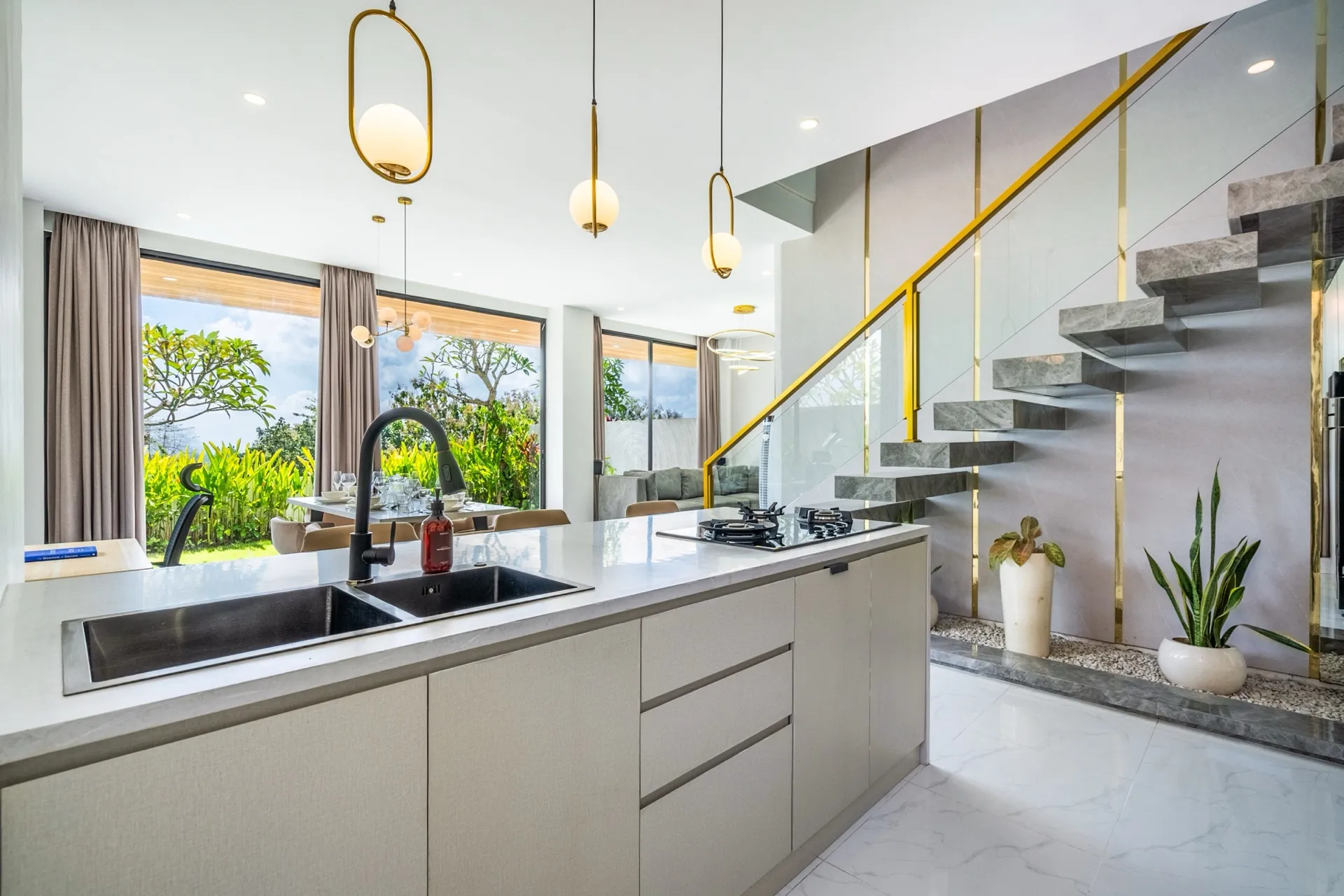 Villa Maisie's kitchen island beside a floating marble staircase with brass detailing